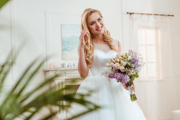 a woman in a wedding dress holds a bouquet of flowers