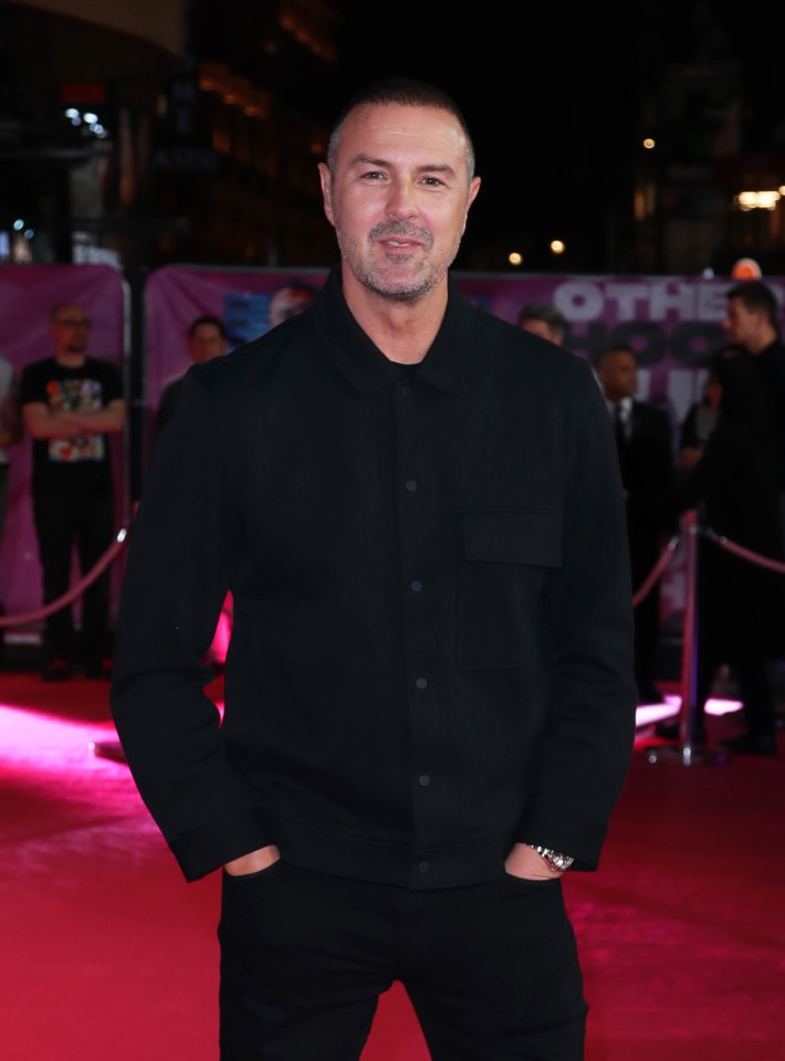 a man in a black shirt stands on a red carpet