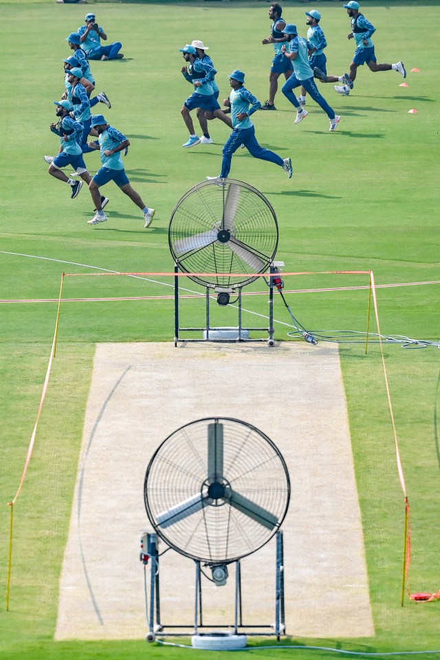 a group of people running on a field with a fan in the foreground