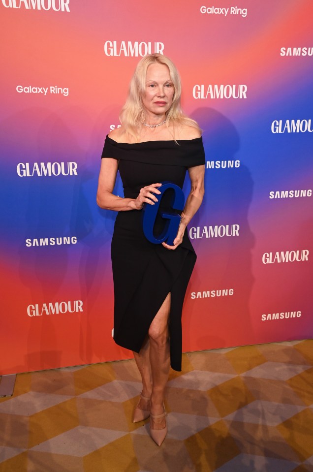 a woman in a black dress stands in front of a glamour sign