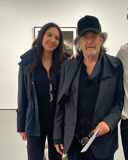 a man and a woman are posing for a picture in front of a wall .