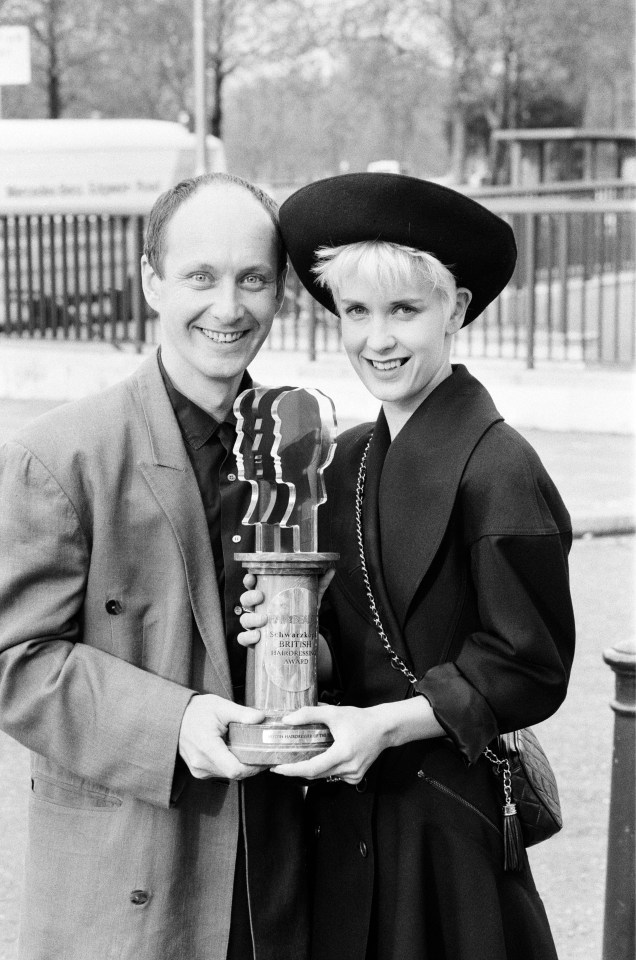 a black and white photo of a man and woman holding a trophy