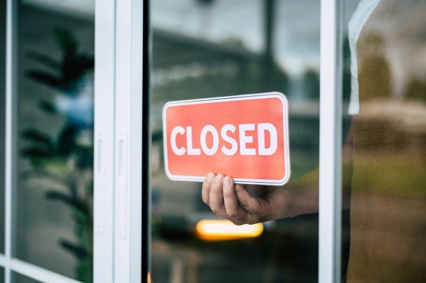 a person is holding a red sign that says closed