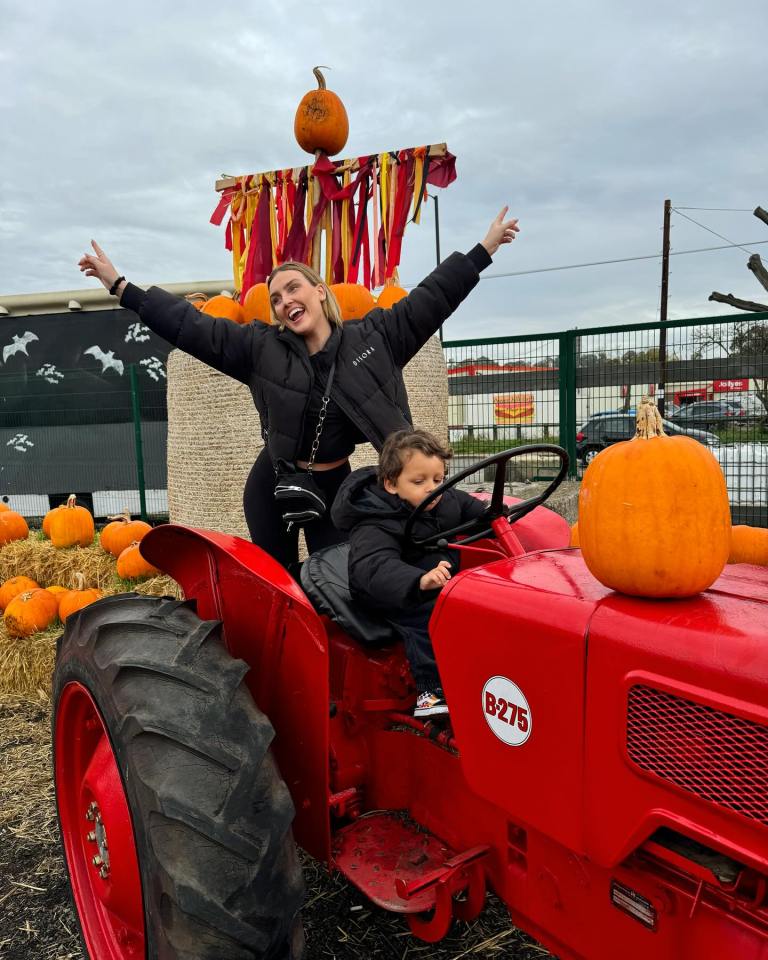 a woman and child are riding a red tractor that says b275