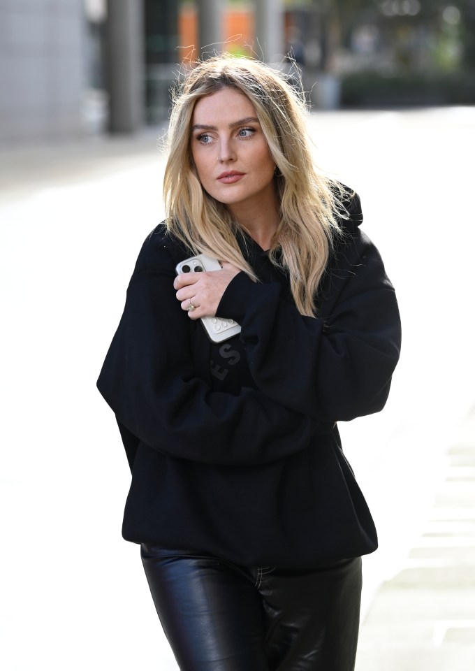 a woman in a black hoodie is holding a cell phone