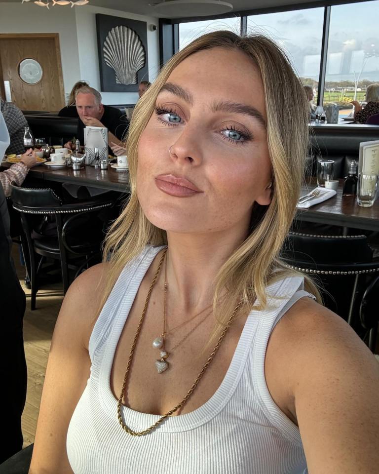 a woman in a white tank top takes a selfie in a restaurant