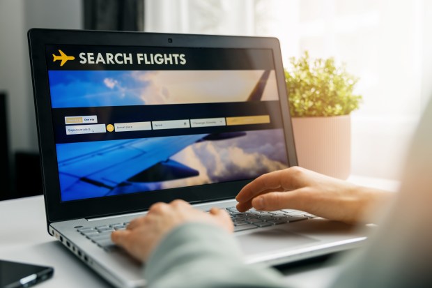 a person is searching for flights on a laptop