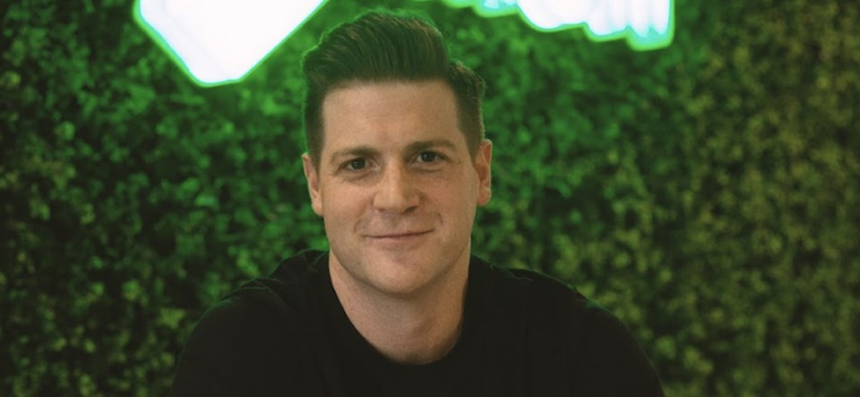 a man in a black shirt is smiling in front of a green wall