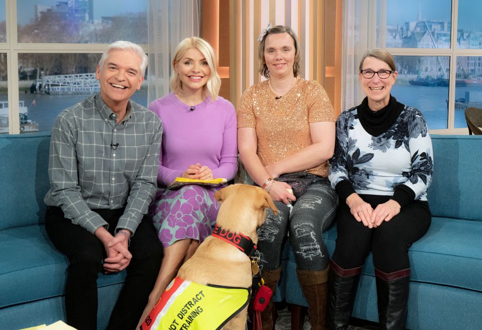 a group of people sitting on a couch with a dog wearing a vest that says " dog "