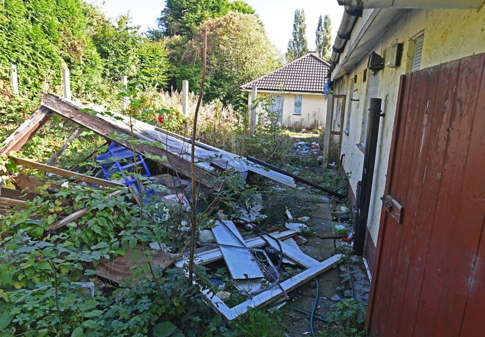 a house with a red door is surrounded by junk