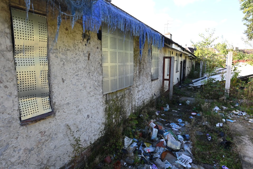 a building with a blue roof has a lot of trash on the ground