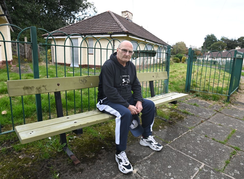 a man sits on a bench in front of a house wearing a hoodie that says ' a ' on it