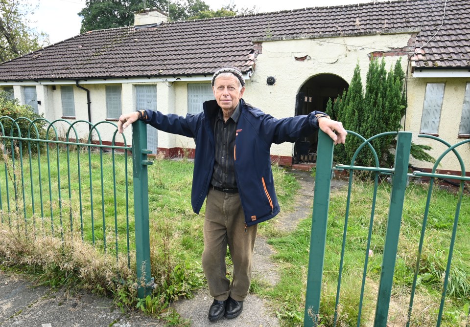 a man in a blue jacket stands in front of a house