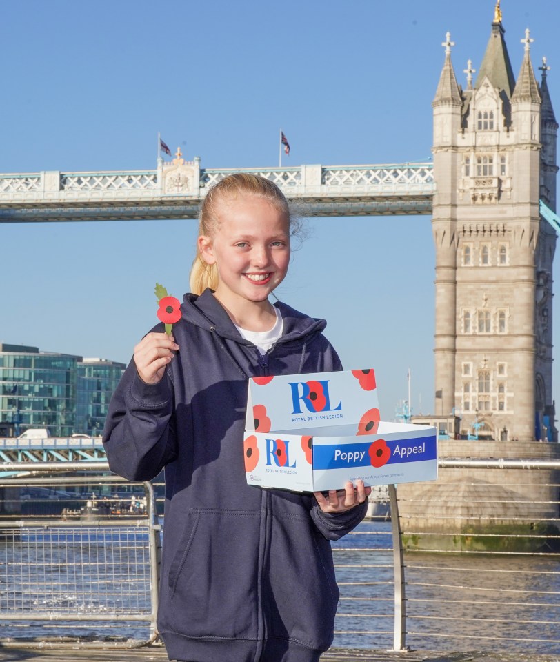 a girl holding a poppy in front of the tower bridge