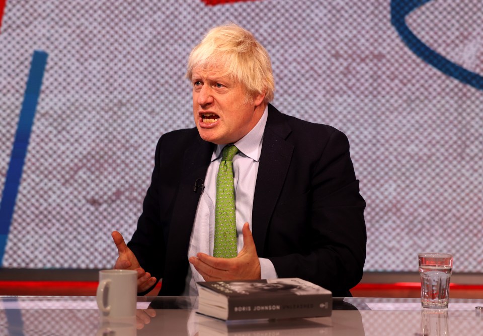 a man sitting at a table with a book that says ' boris johnson ' on it