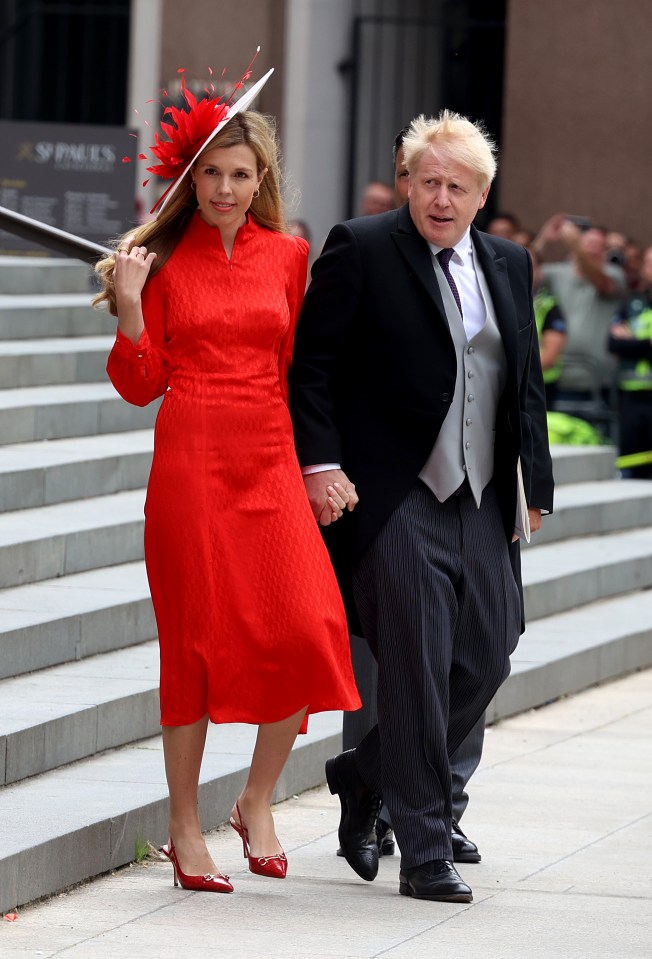 a woman in a red dress holds hands with a man in a suit