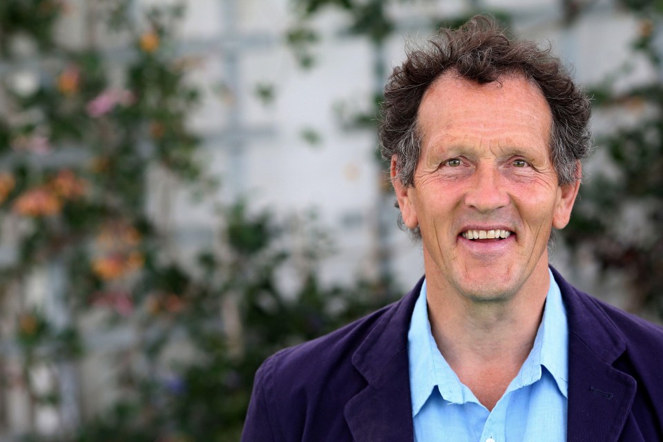 a man in a blue shirt and purple jacket smiles for the camera