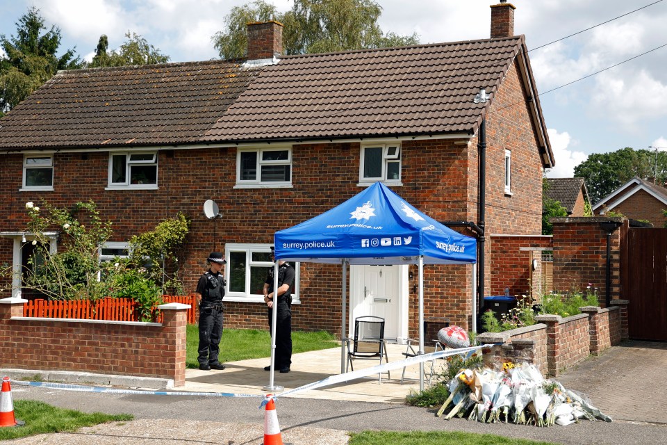 two police officers stand in front of a blue tent that says surrey police uk