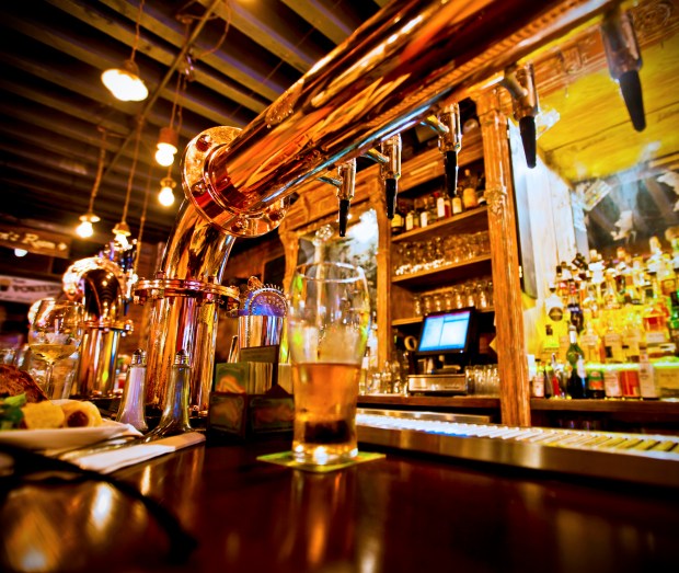 a glass of beer sits on a coaster at a bar