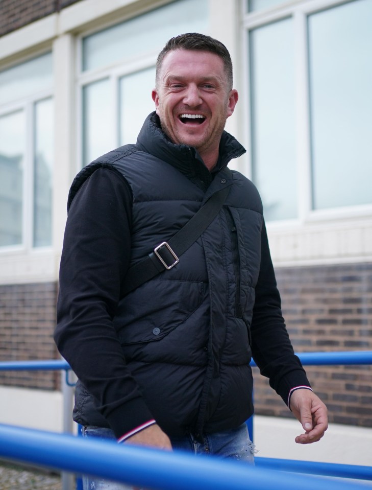 a man wearing a black vest is laughing while standing next to a blue railing