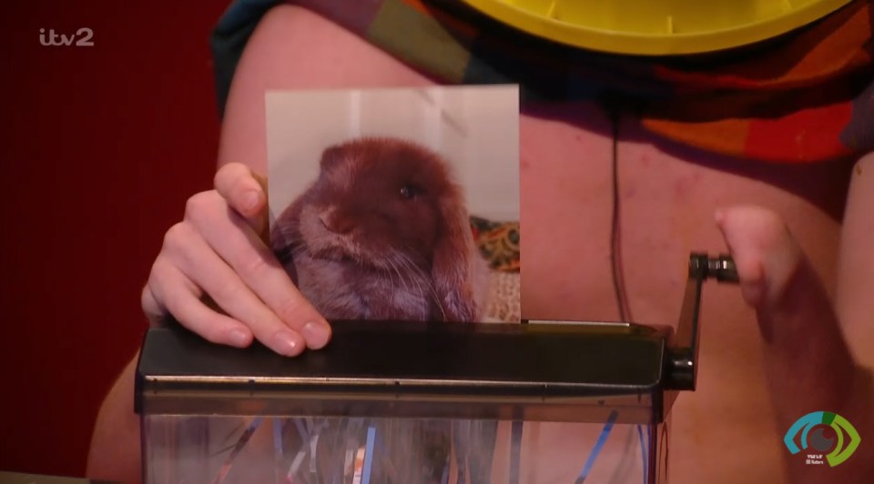 a person holding a picture of a rabbit in front of a itv2 logo