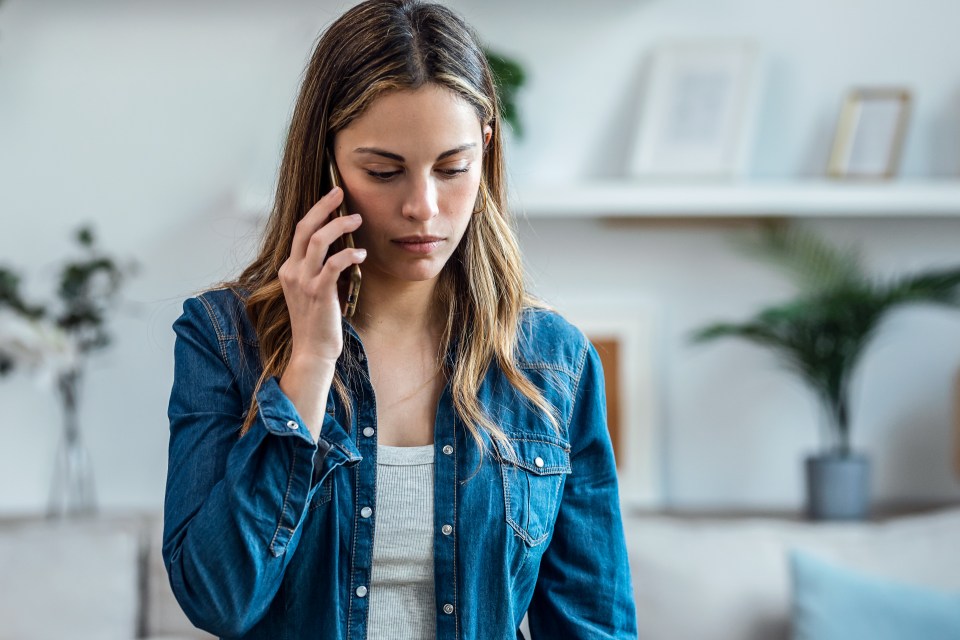 a woman in a denim shirt is talking on a cell phone