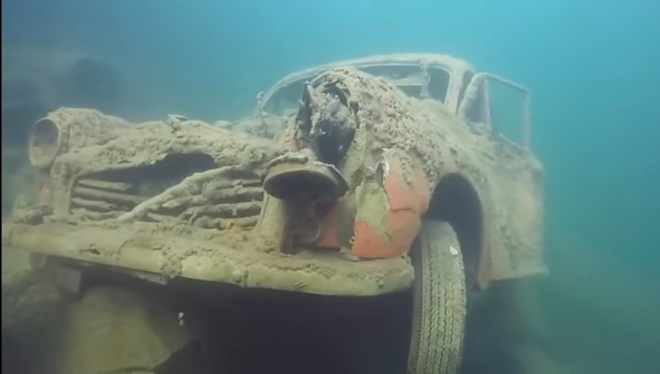 an old car is underwater and covered in dirt