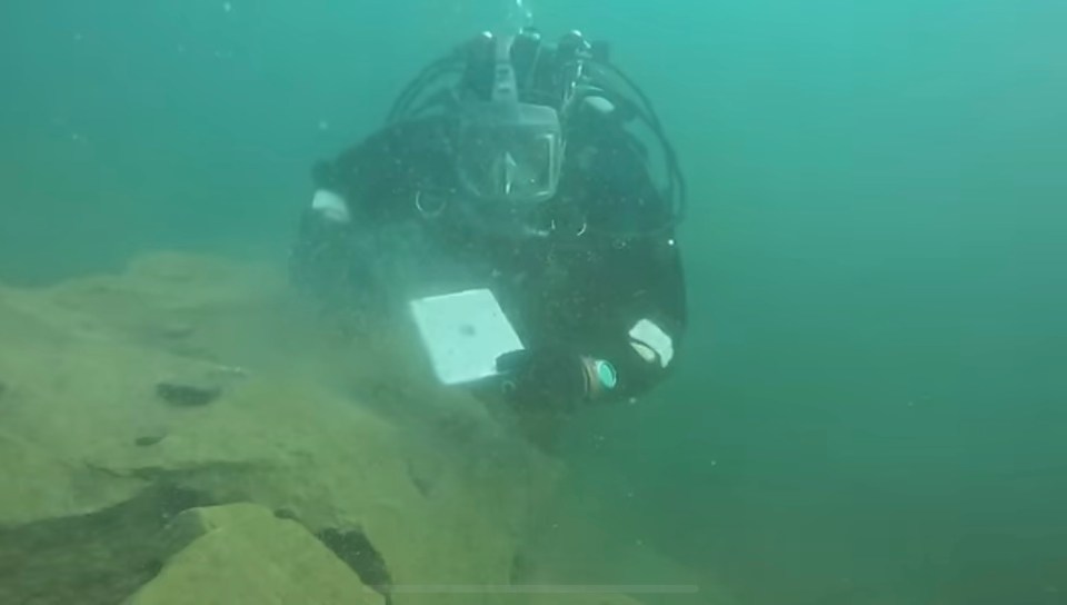 a scuba diver is holding a laptop in the water