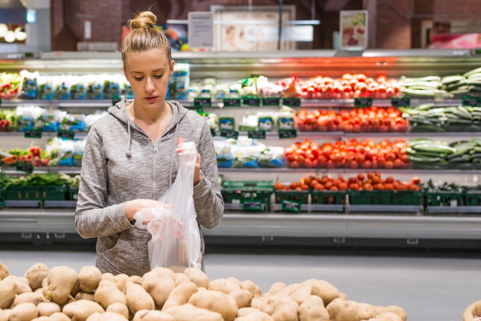 a woman is holding a bag of potatoes in a grocery store