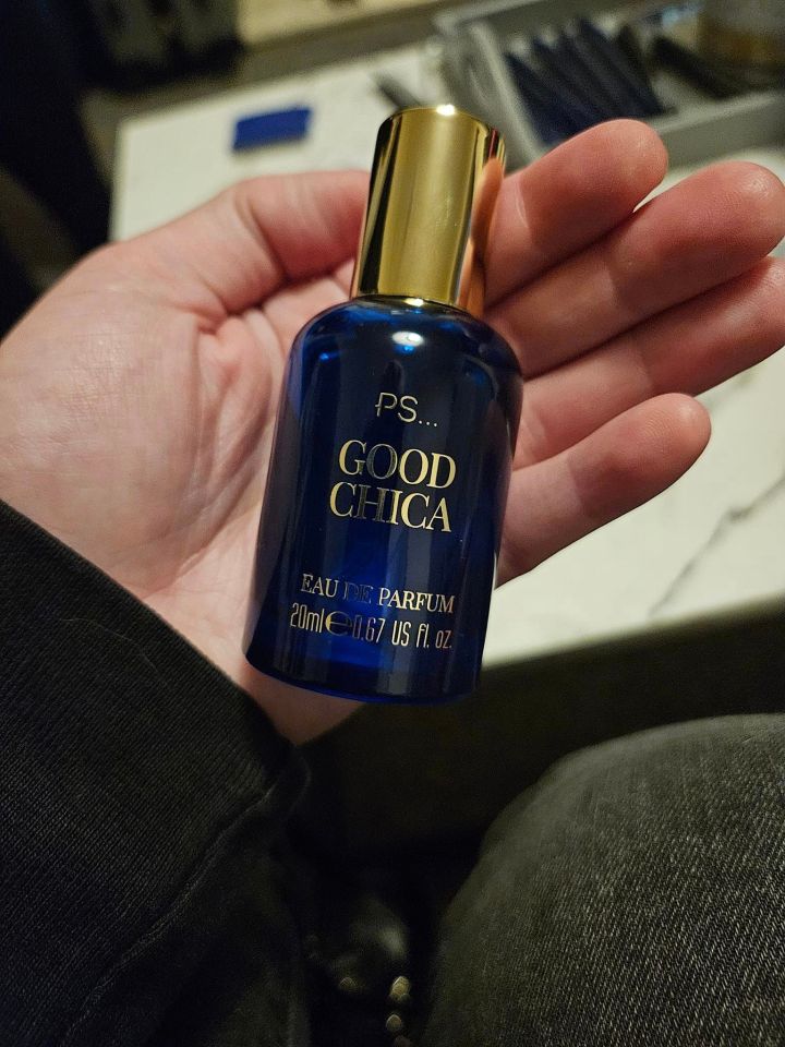 a person is holding a bottle of good chica eau de parfum