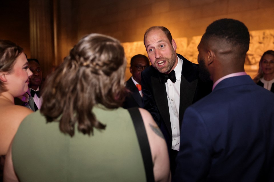 a man in a tuxedo talks to a group of people