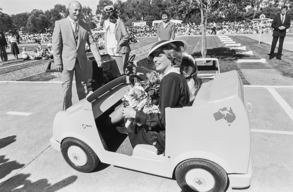 a black and white photo of a woman sitting in a toy car