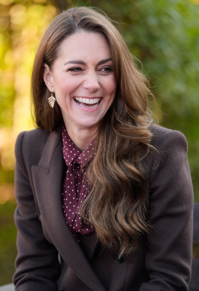 a woman wearing a brown jacket and a polka dot shirt is smiling