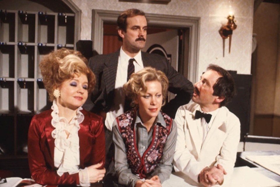 a man in a suit and tie stands between two women and a man in a bow tie