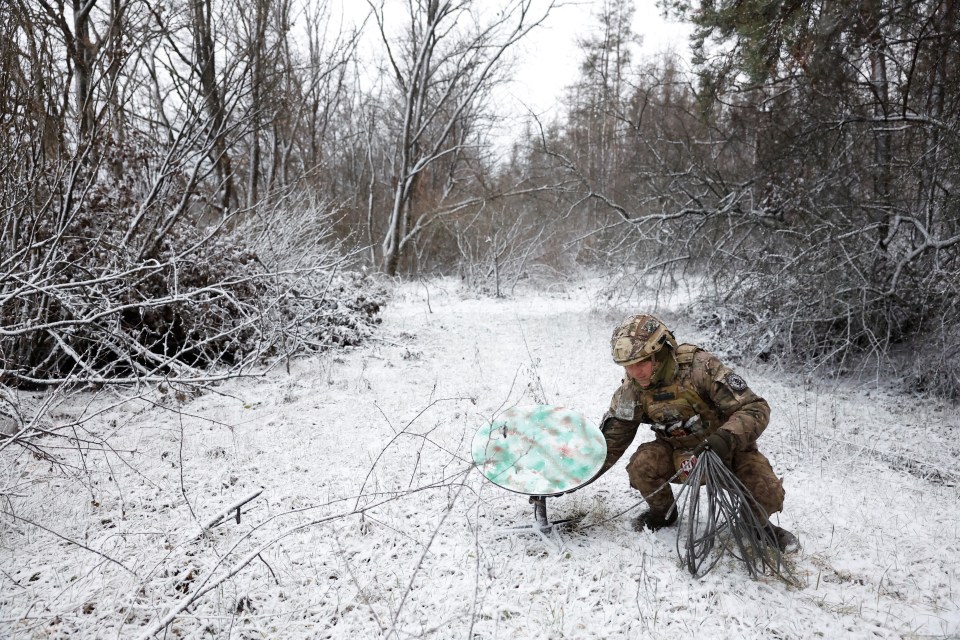 A Ukrainian soldier moves a Starlink dish