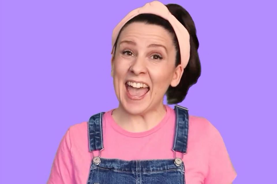 a woman wearing overalls and a pink headband is making a funny face