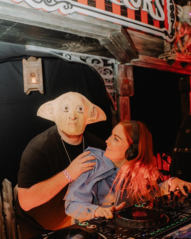 a man wearing a dobby mask holds a woman who is wearing headphones