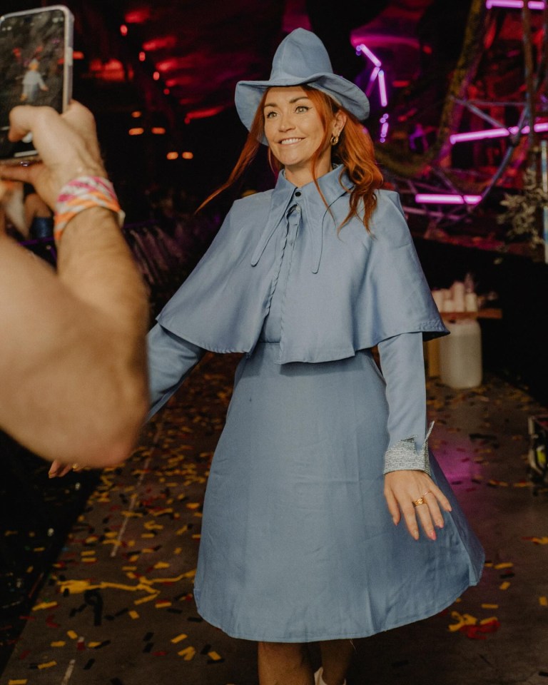 a woman in a blue dress and hat is being photographed