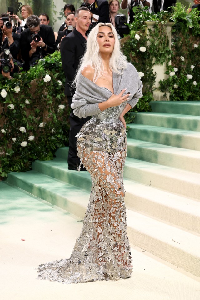 a woman in a silver dress is standing on a staircase