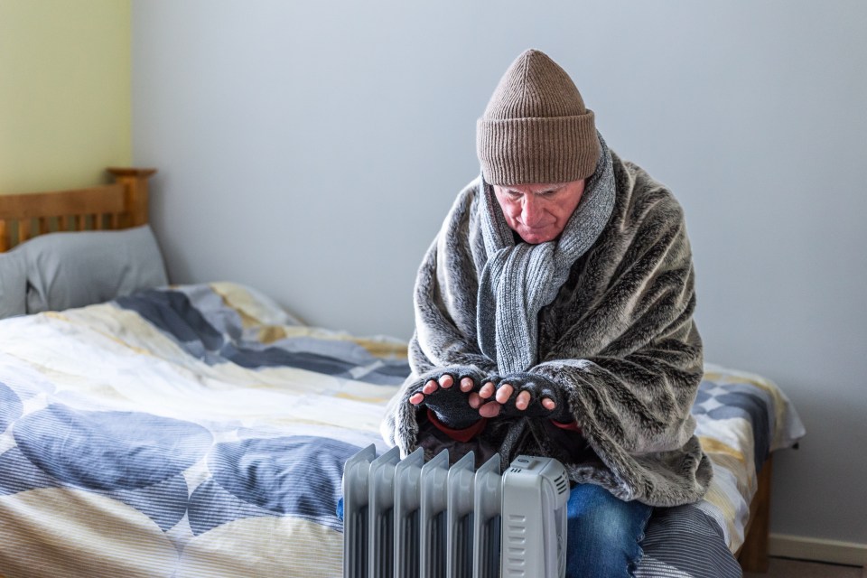 a man wrapped in a blanket is sitting in front of a heater