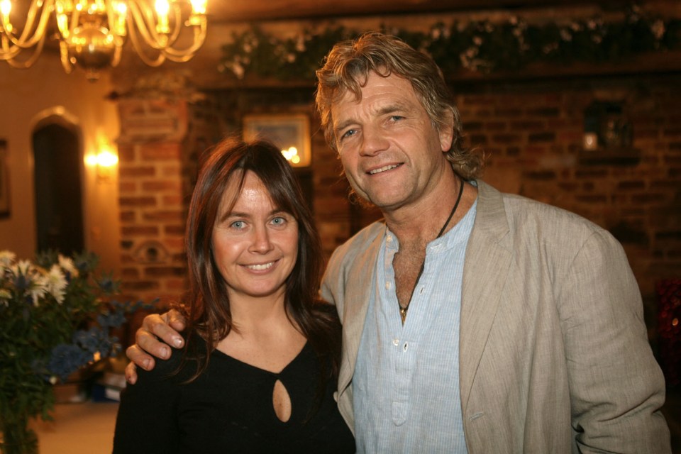 a man and a woman pose for a picture in front of a brick wall