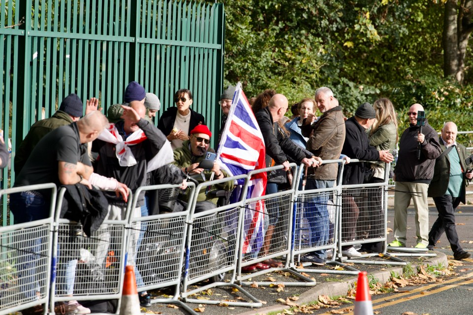 a group of people standing behind a fence holding flags