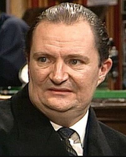 a man in a suit and tie is sitting in front of a pool table .