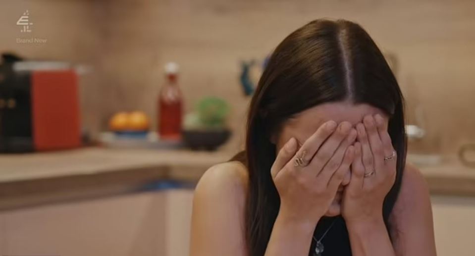 a woman is covering her face with her hands in a kitchen .