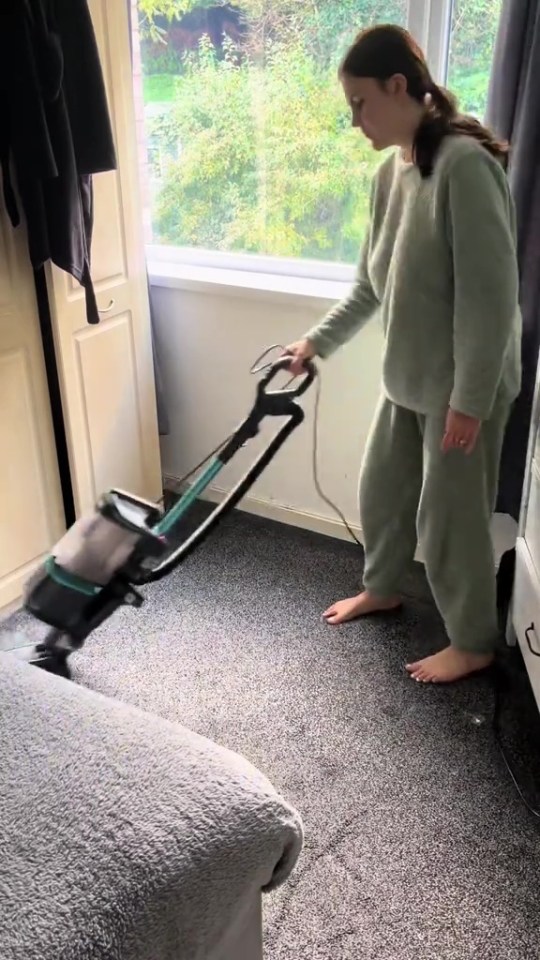 a woman is using a vacuum cleaner to clean the carpet in a bedroom