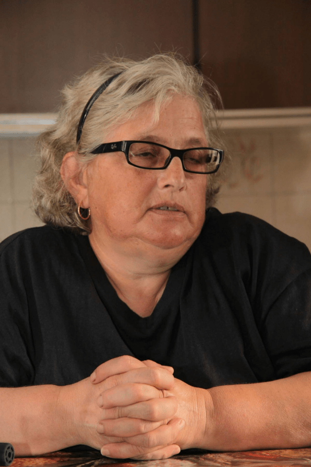 a woman wearing glasses and a black shirt has her hands folded