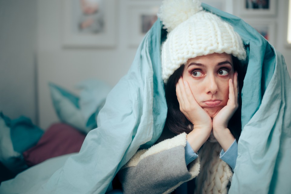 a woman wearing a knitted hat and scarf is wrapped in a blue blanket