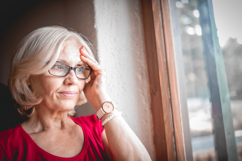 a woman wearing glasses and a watch looks out a window