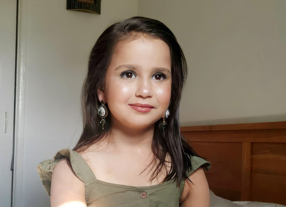 a little girl wearing earrings looks at the camera