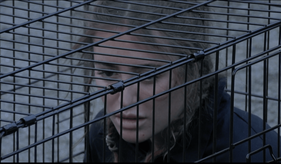 a woman in a black cage looks at the camera